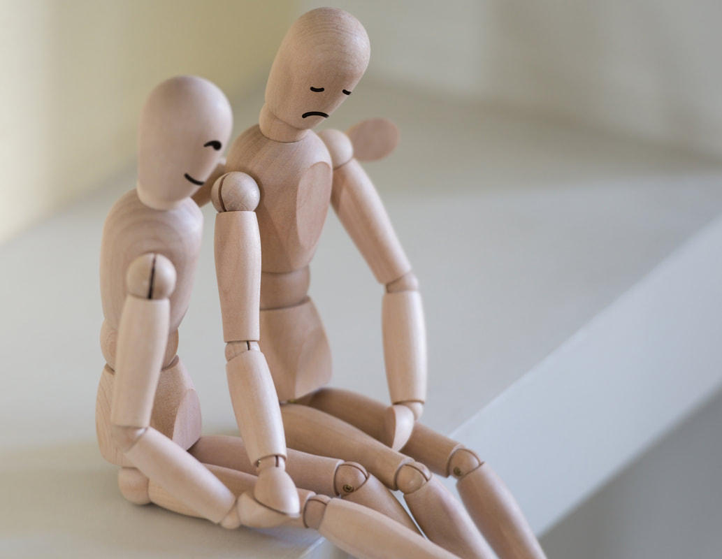 Depressed wooden puppet figure being supported by their friend